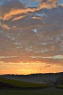 sunrise in the clouds over a dark forest