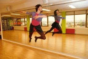 Woman, jumping while dancing, with the reflection in the mirror