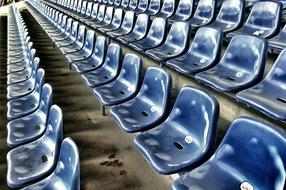 Shiny, blue bucket seats in the football stadium, in light