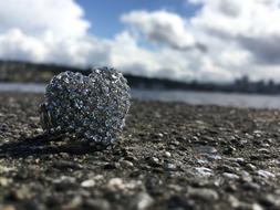 Beautiful ring with the rhinestones, on the ground on the landscape at blue sky with white clouds on background