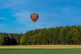 hot air balloon above the green forest on a sunny day