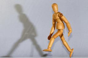 Yellow and brown wooden figure of a person at white background