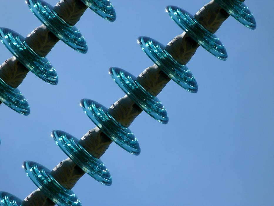 Close-up of the shiny, turquoise electricity insulator, at blue sky on background