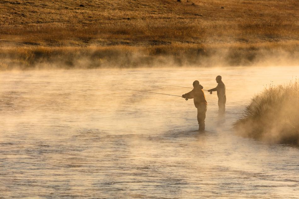 Silhouettes of the fishermen, in the beautiful water in for, with the ripple, near the colorful and beautiful shore, in the Yellowstone National Park, Wyoming, USA