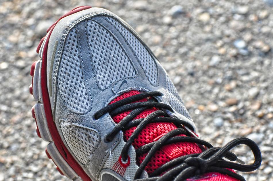 Close-up of the colorful sports shoe, with the laces, on the foot, above the colorful ground