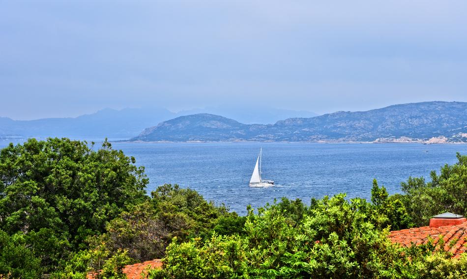 sailboat on the sea near the hilly coast