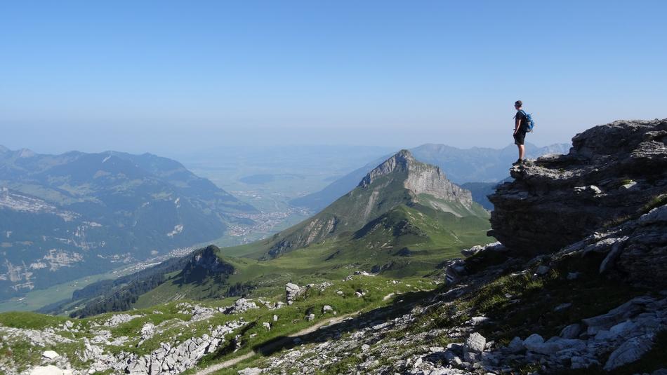 climber stands on a cliff in the background of the Alpine Valley