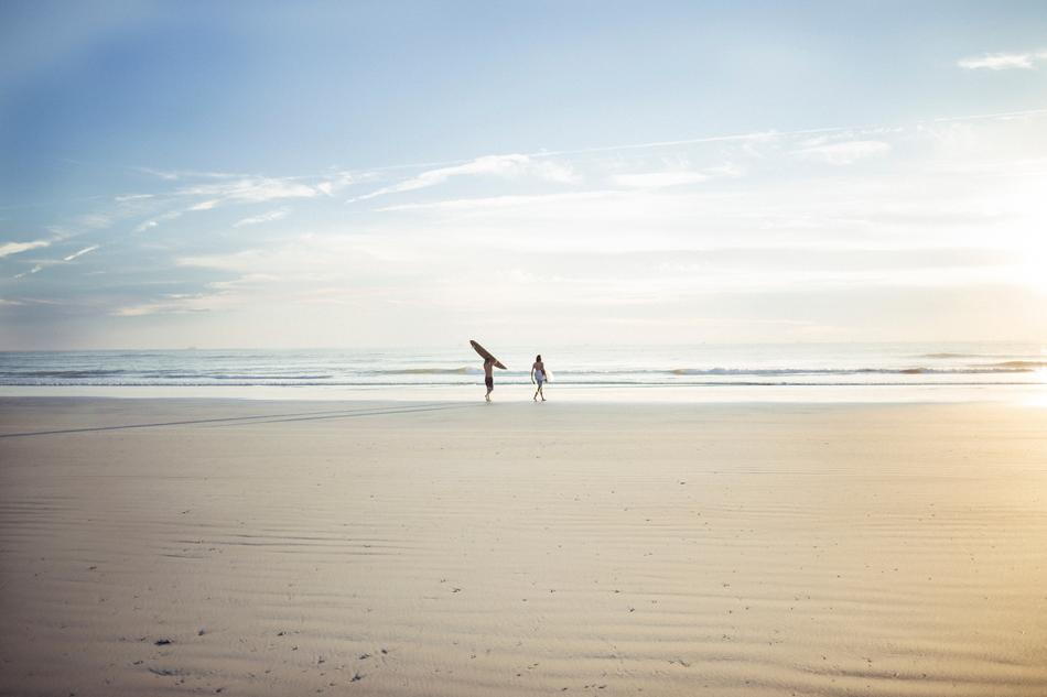 photo of two surfers on the horizon
