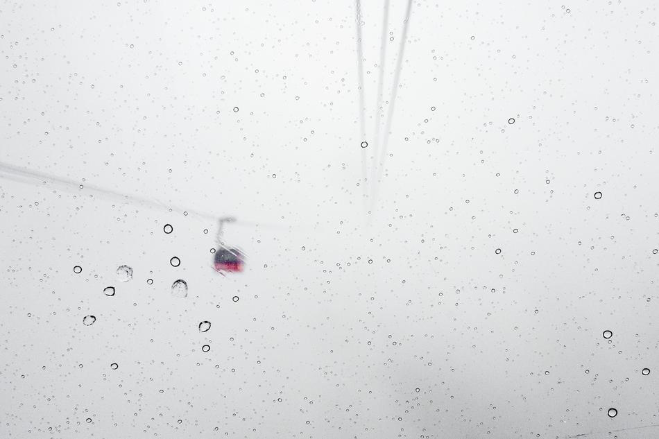 view of cable car on line through window with drops of water
