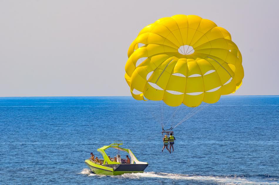 parasailing, parachute with two people towed behind motor boat