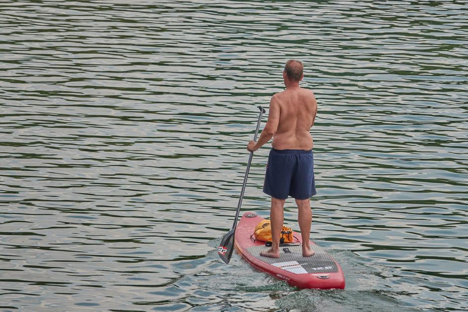 Back view of a man, rowing on the beautiful water with ripple