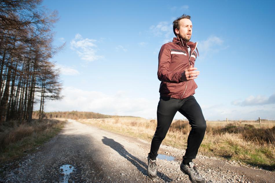 man runs along the road near trees