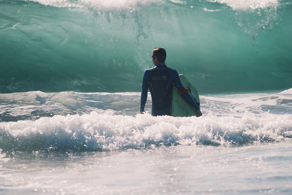 surfer stands in Sea in front of wave
