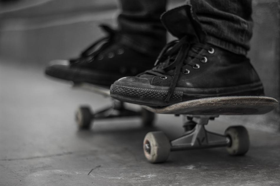 the legs of a guy in black sneakers on a skateboard