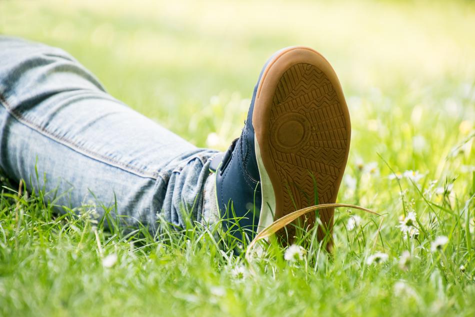 leg in jeans and sneaker lays on Grass
