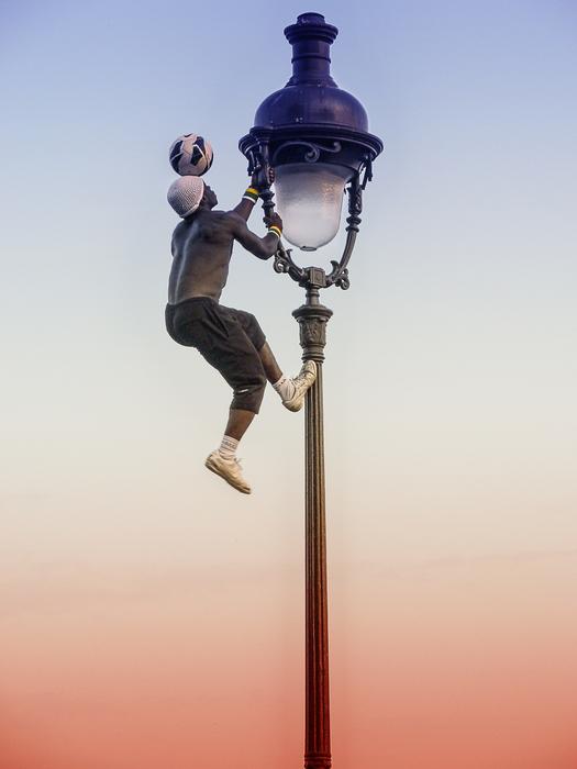man with ball on street lamp