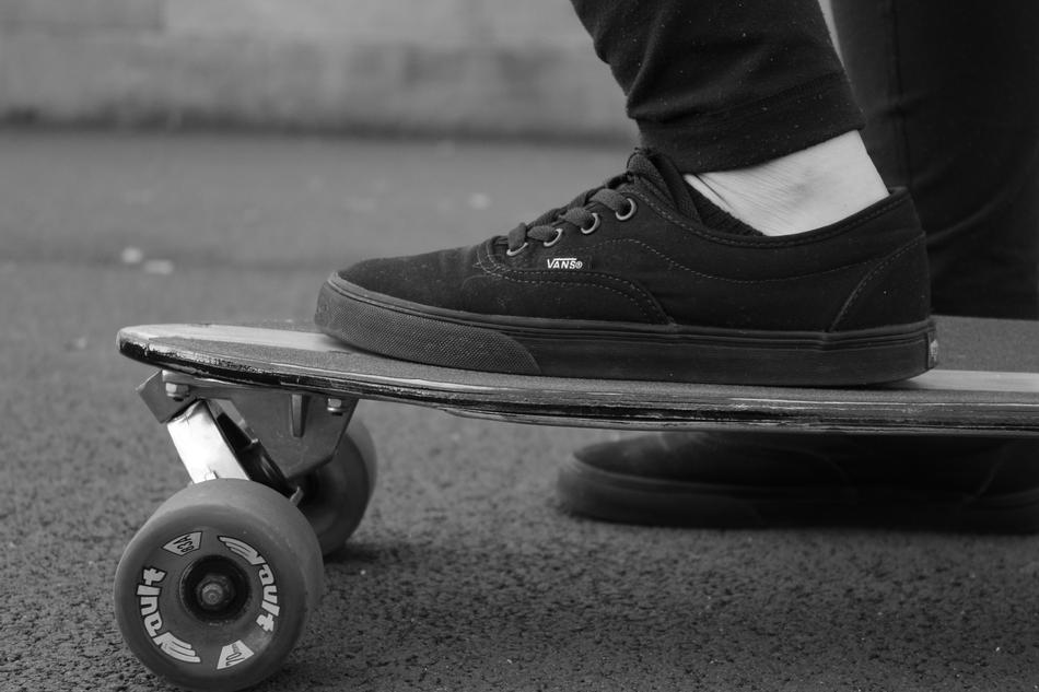 foot on skateboard in black and white background