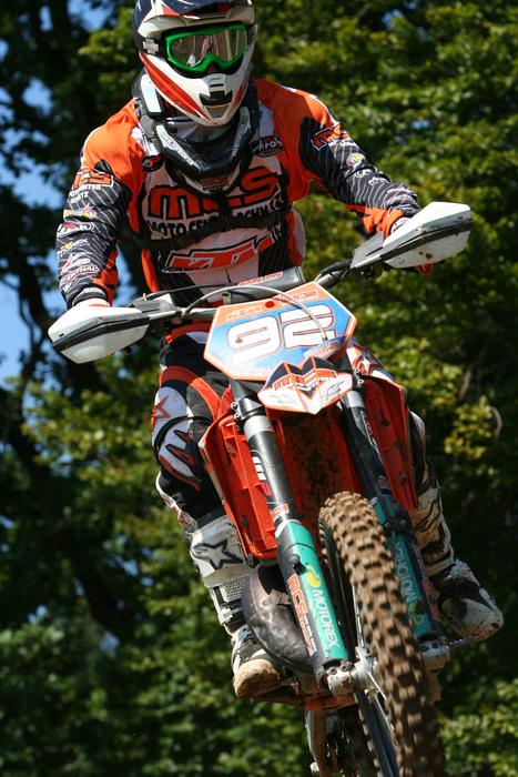 Person, on the colorful motorbike, in jump, among the green trees