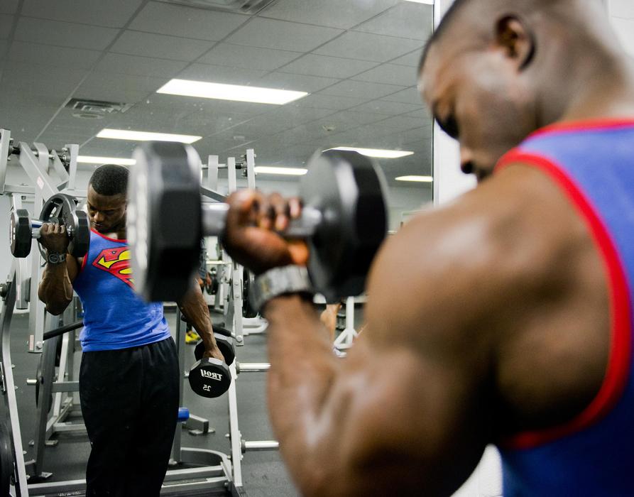bobebuilder raises dumbbells in front of a mirror