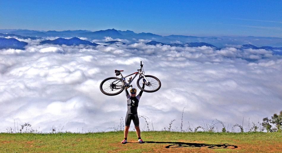 man with a bicycle above the clouds in the mountains