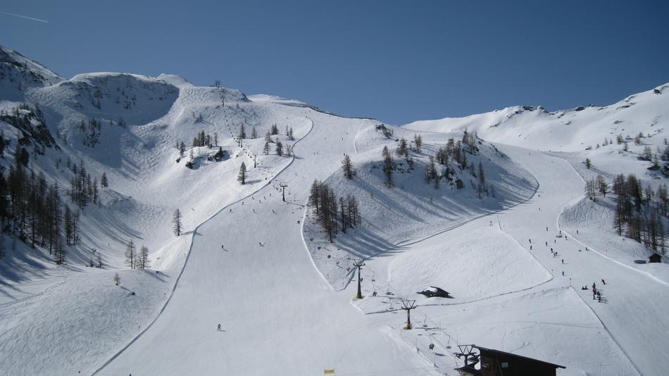 Beautiful landscape of the ski run on the snowy mountains, with trees, at blue sky in Austria, under the blue sky