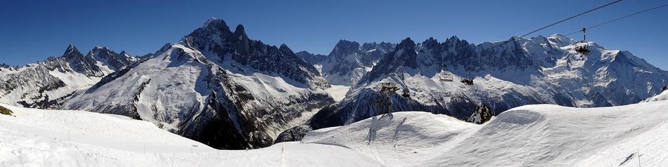 Beautiful panoramic view of the snowy Alps in light, under the blue sky