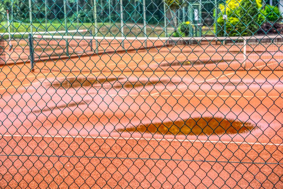 Wet tennis court with the colorful plants around