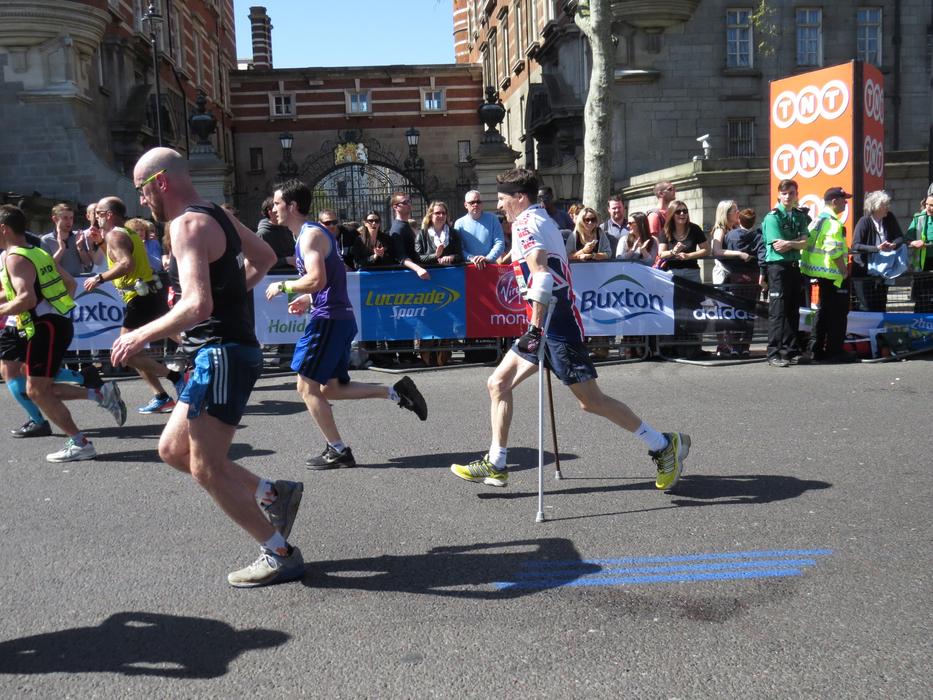 man with crutches on runs on competition in city