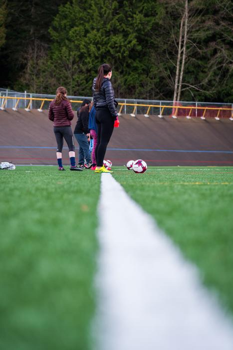Girls, practicing soccer on the green and white field