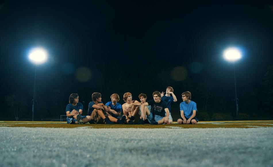 group of friends on the stadium field in the beams of spotlights