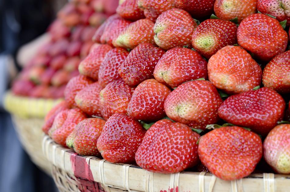 lot of ripe juicy strawberries in wicker bowls in a blurred background