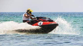 Person in helmet, riding on the jet ski, in the water, with the waves