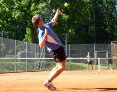 Tennis players, playing on the court, among the green trees, in light