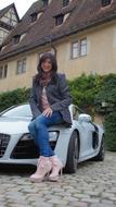girl is sitting on the hood of a luxury sports car