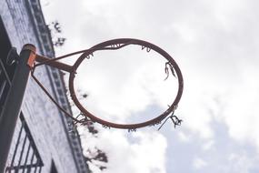 Close-up of a rim, without the net, near the building, at blue sky with white clouds on background