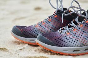 Close-up of the colorful sports shoes, with the grey laces, on the sand