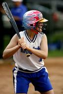 Softball batter female player, with the colorful helmet, on the competition