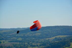 a man with a parachute flying over the forest