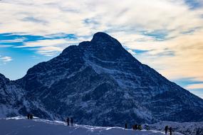 People on the beautiful, snowy mountains, under the sky with the clouds, in the winter