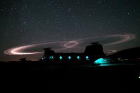 Beautiful landscape with the Military Chinook helicopter with turquoise lights and colorful starry skies, at might