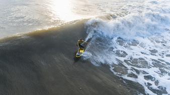 Person, surfing on the beautiful water with waves, at colorful sunset
