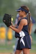 Profile portrait of the pitcher girl player on the green grass