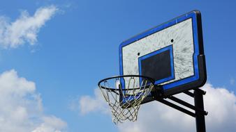 Blue and white basket for basketball, at blue sky with white clouds on background