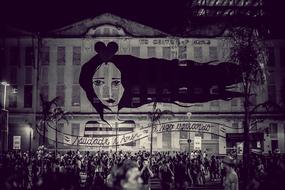 Black and white photo with the people in the beautiful boulevard, with the girl painting on the building in Rio, Brazil, in 2016