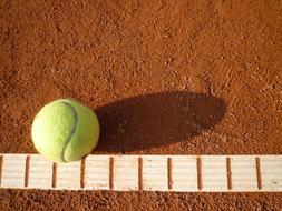 yellow tennis ball on the edge of the court