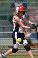 Softball female batter, wearing helmet, on the competition