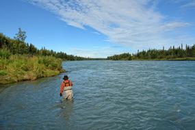 man fishing on a river in alaska