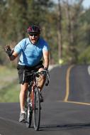 Cyclist, riding on the bike, on the road, with yellow line, among the beautiful, green trees, in Canada