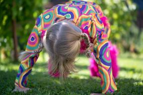 Blonde girl, in the colorful clothing, doing exercises, among the beautiful, green plants