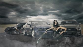 Woman in black costume, near the shiny cars on the road, under the cloudy sky, among the fields